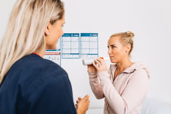 Health professional helping patient with peak flow meter
