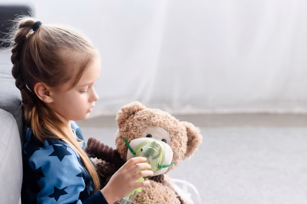 Child holding mask to teddy bear