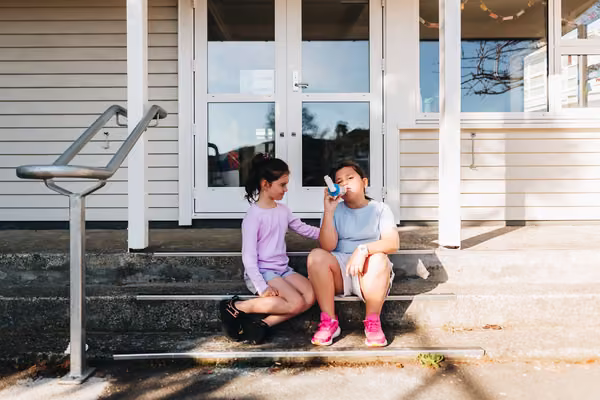 Student on school steps having asthma inhaler
